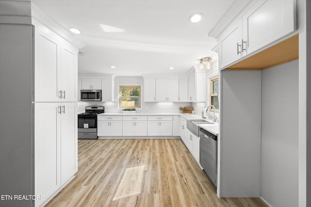 kitchen featuring decorative backsplash, white cabinetry, light hardwood / wood-style flooring, sink, and stainless steel appliances