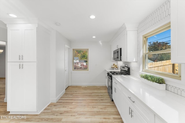 kitchen featuring white cabinets, appliances with stainless steel finishes, light wood-type flooring, and plenty of natural light