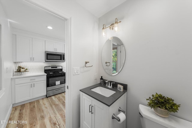 bathroom featuring toilet, hardwood / wood-style flooring, sink, and backsplash