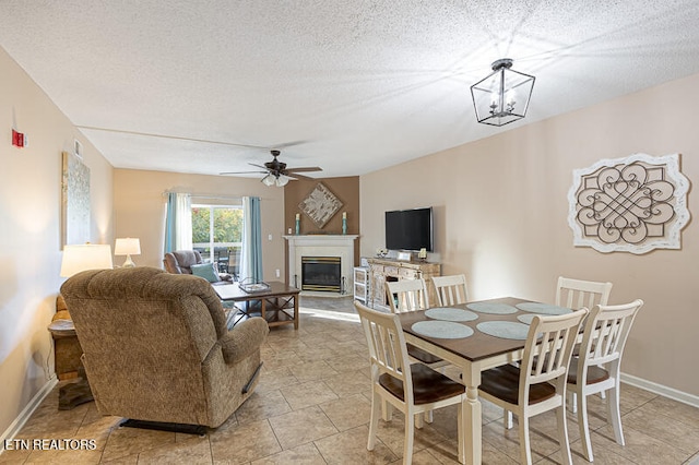 dining space featuring a textured ceiling, ceiling fan with notable chandelier, and light tile patterned floors