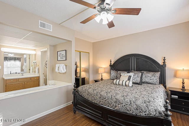 bedroom with dark hardwood / wood-style flooring, a closet, sink, and ceiling fan