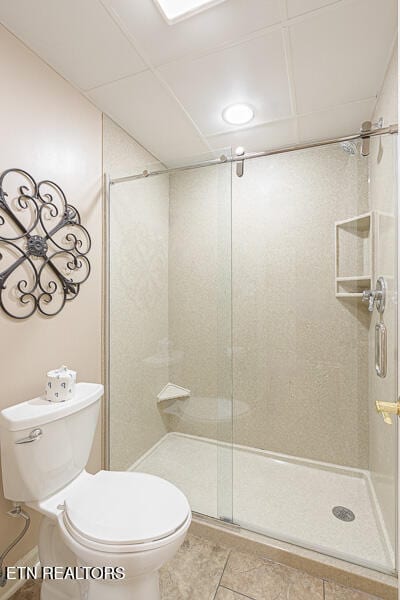 bathroom featuring tile patterned floors, a shower with shower door, and toilet