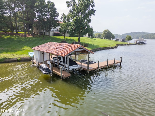 view of dock with a lawn and a water view