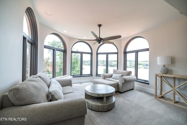 living room with a water view, light carpet, a wealth of natural light, and ceiling fan