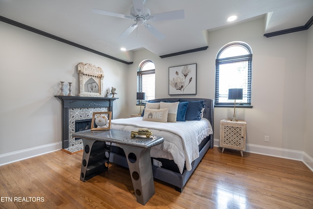 bedroom with a high end fireplace, hardwood / wood-style floors, ornamental molding, and ceiling fan