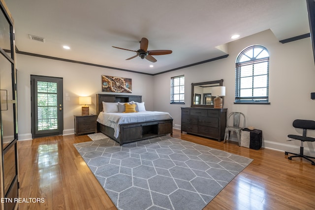 bedroom featuring multiple windows, wood-type flooring, crown molding, and ceiling fan