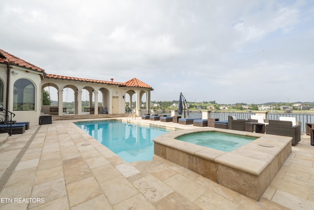 view of swimming pool with a patio, an in ground hot tub, and a water view