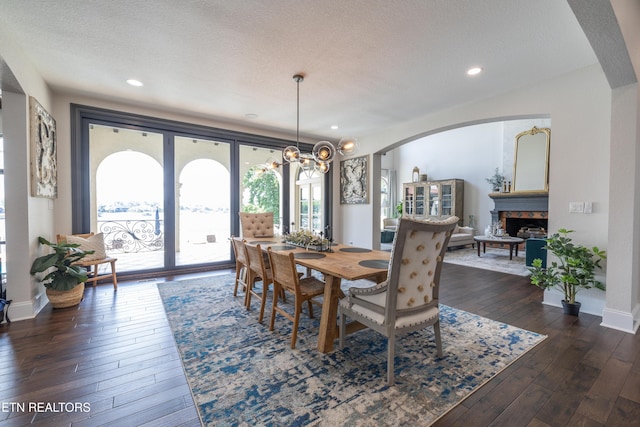 8719 Inlet Dr, Knoxville, TN 37922 - dining space with arched walkways, dark wood-style flooring, a fireplace, a chandelier, and baseboards