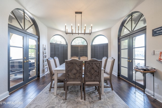 dining space with french doors, a healthy amount of sunlight, a chandelier, and dark wood-type flooring