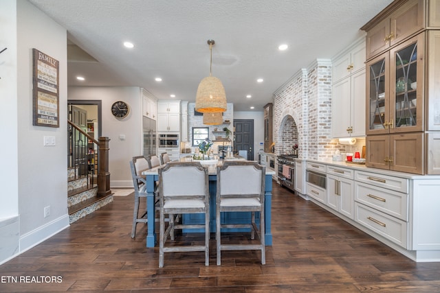 kitchen featuring a large island, dark wood-type flooring, white cabinetry, and hanging light fixtures