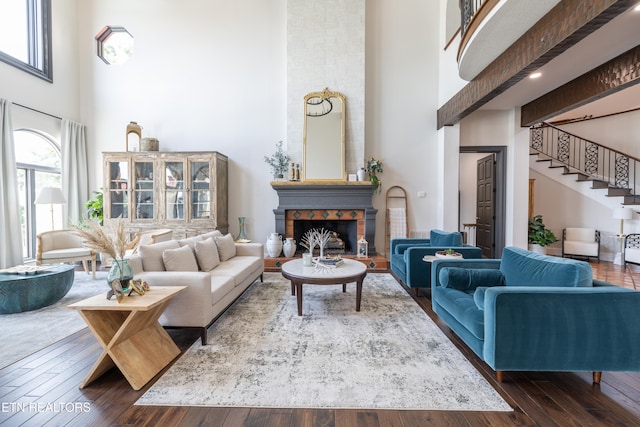 living room with beam ceiling, a fireplace, dark hardwood / wood-style floors, and a towering ceiling