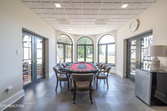 dining area with french doors, a drop ceiling, and a healthy amount of sunlight