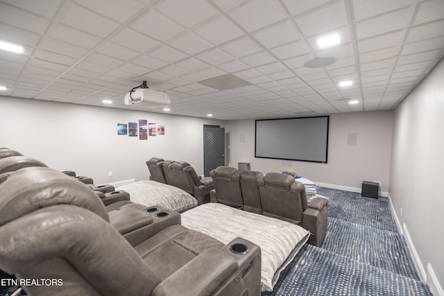 carpeted cinema with a paneled ceiling