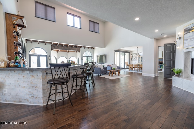 kitchen featuring a premium fireplace, a textured ceiling, dark wood-type flooring, and a high ceiling