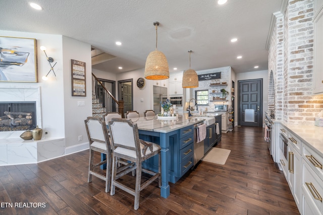 kitchen with white cabinetry, a kitchen bar, stainless steel appliances, decorative light fixtures, and blue cabinets