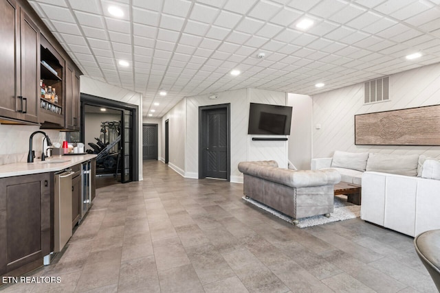 living room featuring wet bar and a paneled ceiling