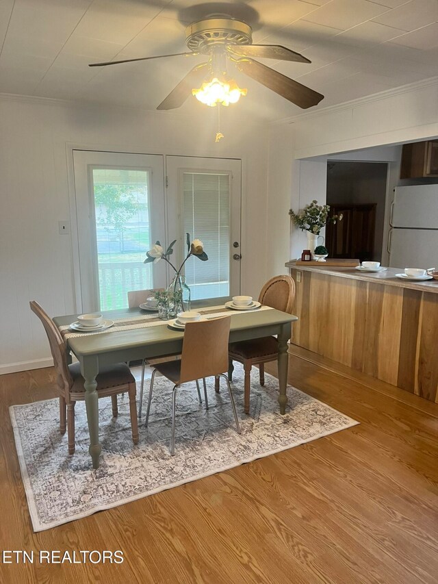 dining space with hardwood / wood-style flooring, ceiling fan, and crown molding