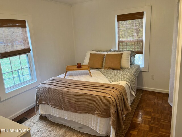 bedroom featuring multiple windows and dark parquet flooring