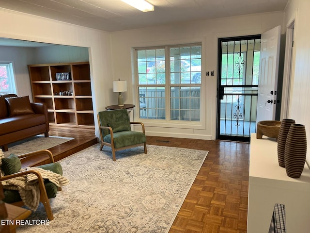 living room featuring a healthy amount of sunlight and dark parquet flooring