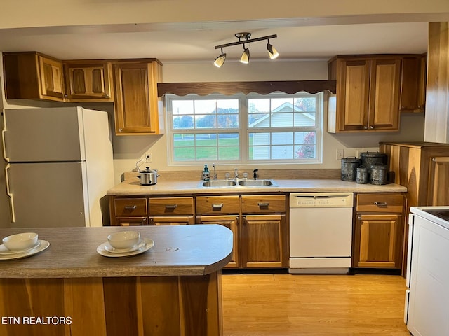 kitchen with light wood-type flooring, white appliances, and sink