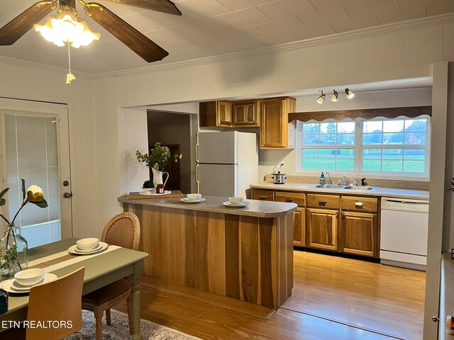 kitchen with light wood-type flooring, white appliances, crown molding, and sink