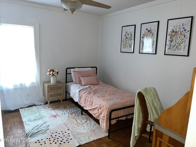 bedroom with dark parquet floors, multiple windows, and ceiling fan