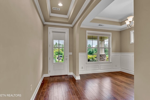 doorway to outside with ornamental molding, a tray ceiling, dark wood-type flooring, and plenty of natural light