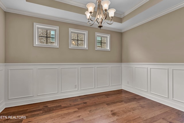 unfurnished room featuring hardwood / wood-style floors, crown molding, a chandelier, and a raised ceiling