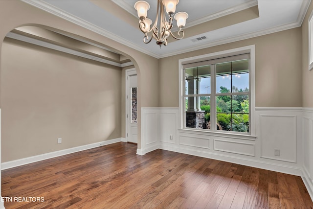 empty room featuring crown molding, a raised ceiling, a chandelier, and hardwood / wood-style floors