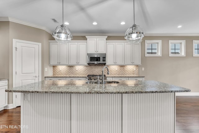 kitchen featuring dark hardwood / wood-style flooring, pendant lighting, white cabinets, light stone counters, and a kitchen island with sink