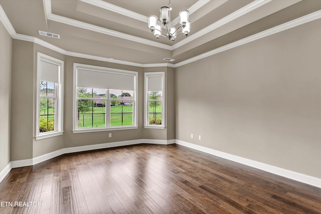 spare room with dark wood-type flooring, crown molding, a tray ceiling, and a chandelier