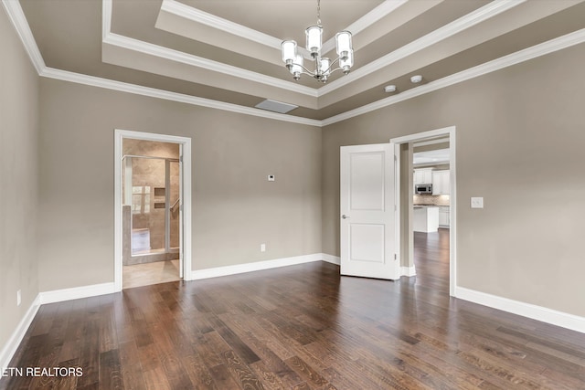 unfurnished room with ornamental molding, dark wood-type flooring, and a raised ceiling