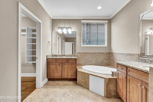 bathroom with vanity, ornamental molding, a relaxing tiled tub, and tile patterned flooring