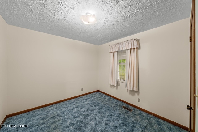 spare room featuring a textured ceiling and dark carpet