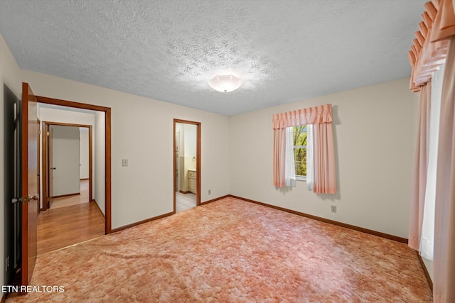 unfurnished bedroom featuring connected bathroom, a textured ceiling, and light hardwood / wood-style flooring