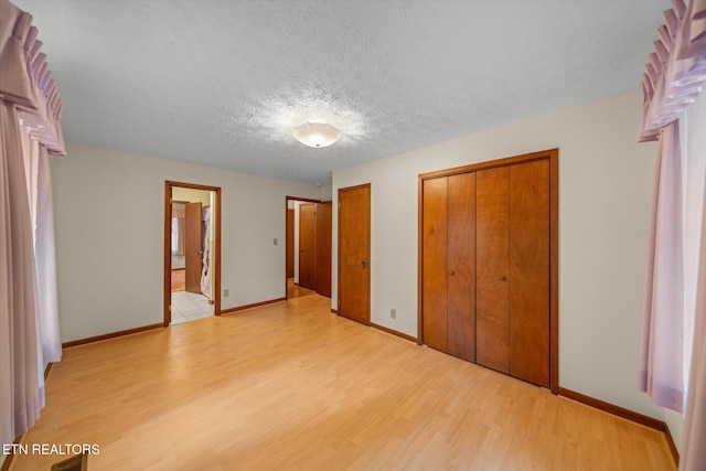 unfurnished bedroom featuring light wood-type flooring, a textured ceiling, and ensuite bathroom