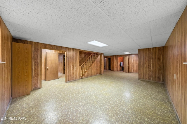 basement with a paneled ceiling and wooden walls