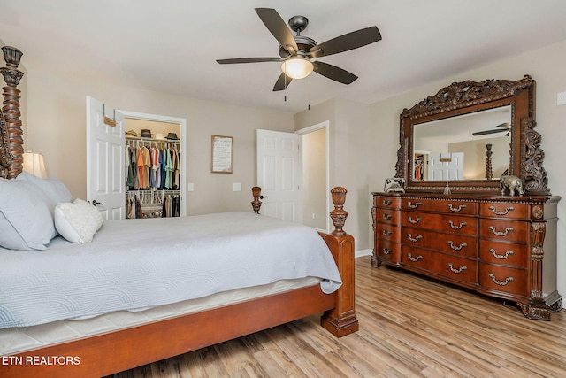 bedroom with a spacious closet, light hardwood / wood-style flooring, a closet, and ceiling fan