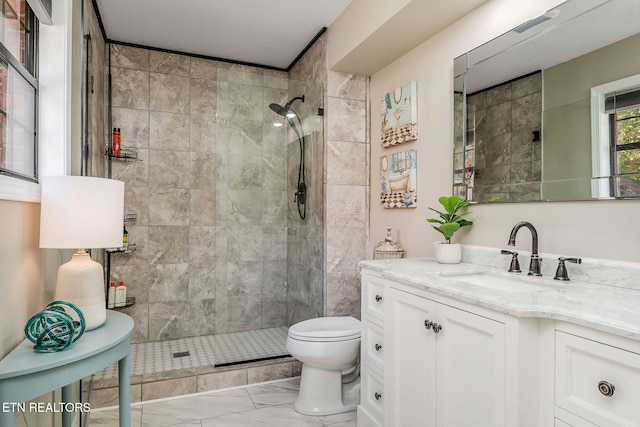 bathroom with vanity, toilet, and a tile shower