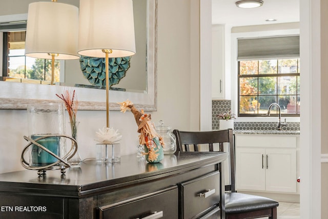 interior space with white cabinetry, tasteful backsplash, sink, and plenty of natural light