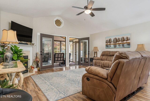 living room with light hardwood / wood-style floors, lofted ceiling, french doors, and ceiling fan