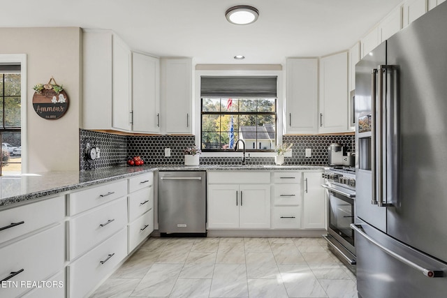 kitchen with a healthy amount of sunlight, premium appliances, and white cabinets