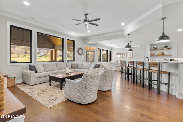 living room with light hardwood / wood-style floors, ceiling fan, ornamental molding, and sink