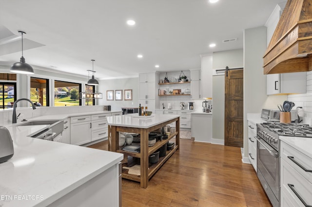 kitchen with white cabinetry, a barn door, backsplash, pendant lighting, and high end range