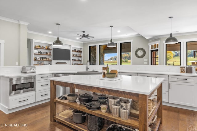 kitchen featuring a large island, sink, hanging light fixtures, dark wood-type flooring, and stainless steel dishwasher