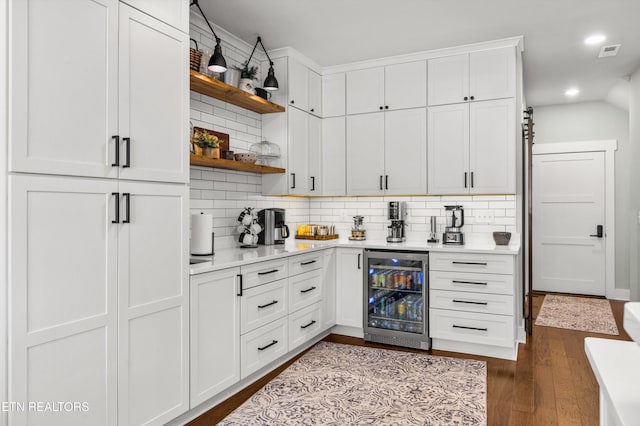 interior space with decorative backsplash, white cabinetry, beverage cooler, and wood-type flooring