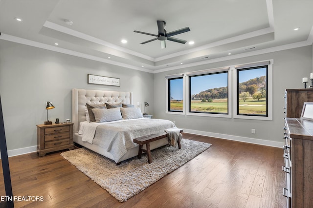 bedroom with ceiling fan, a raised ceiling, and dark wood-type flooring