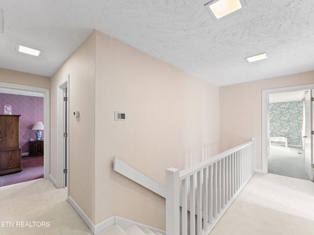 hallway featuring light carpet and a textured ceiling