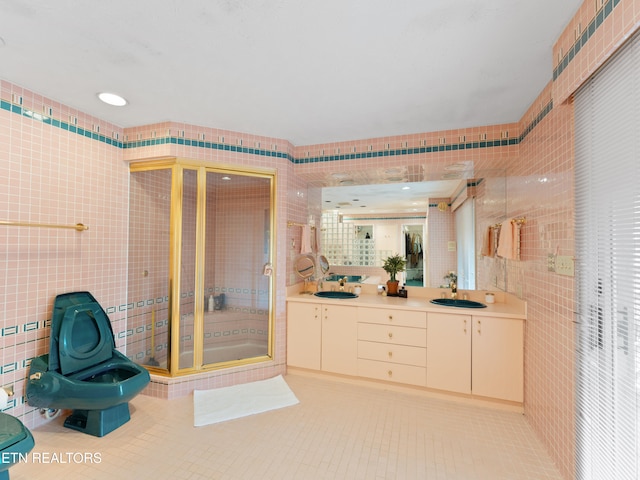 bathroom featuring tile patterned floors, a bidet, a shower with door, vanity, and tile walls