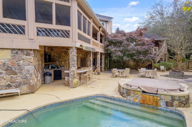 view of pool featuring an outdoor bar, a patio area, and a fire pit